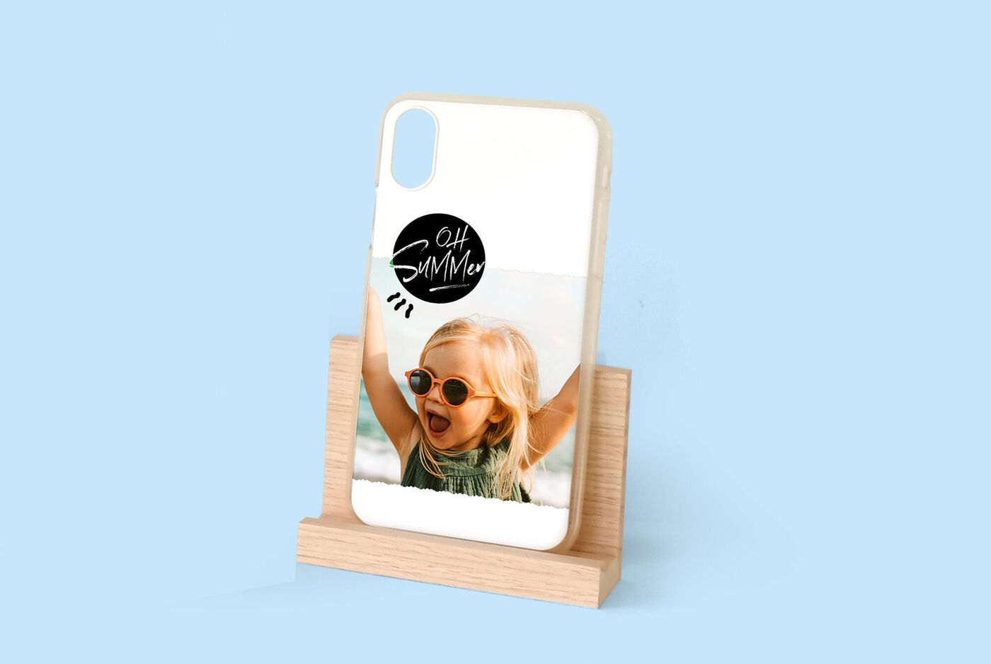 Une coque de téléphone personnalisée sur un support en bois, avec un enfant souriant en arrière-plan.