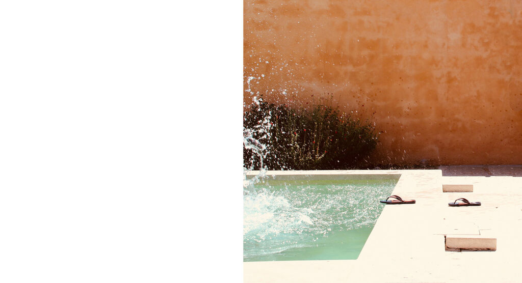 Des gouttes d'eau éclaboussent d'une piscine, des sandales sont à proximité, image d'un moment de vacances détendu.