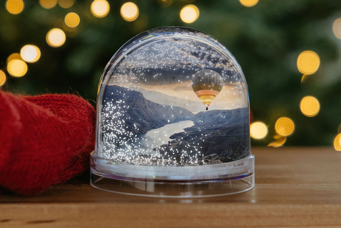 Boule à neige avec paysage de montagne et montgolfière devant des arrière-plans lumineux.
