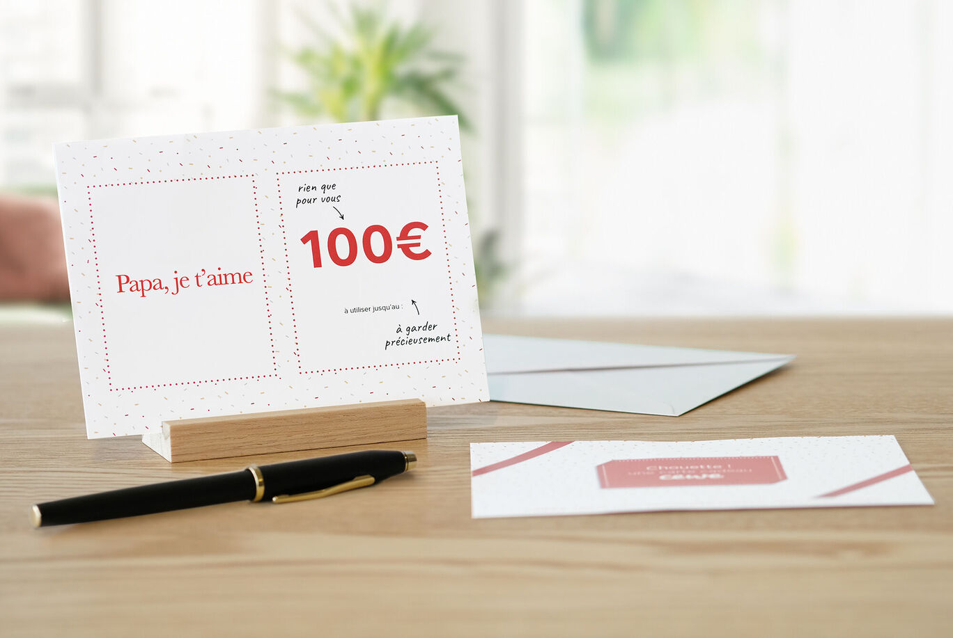 Une carte-cadeau soigneusement conçue de 100 euros avec l'inscription 'Papa, je t’aime'.