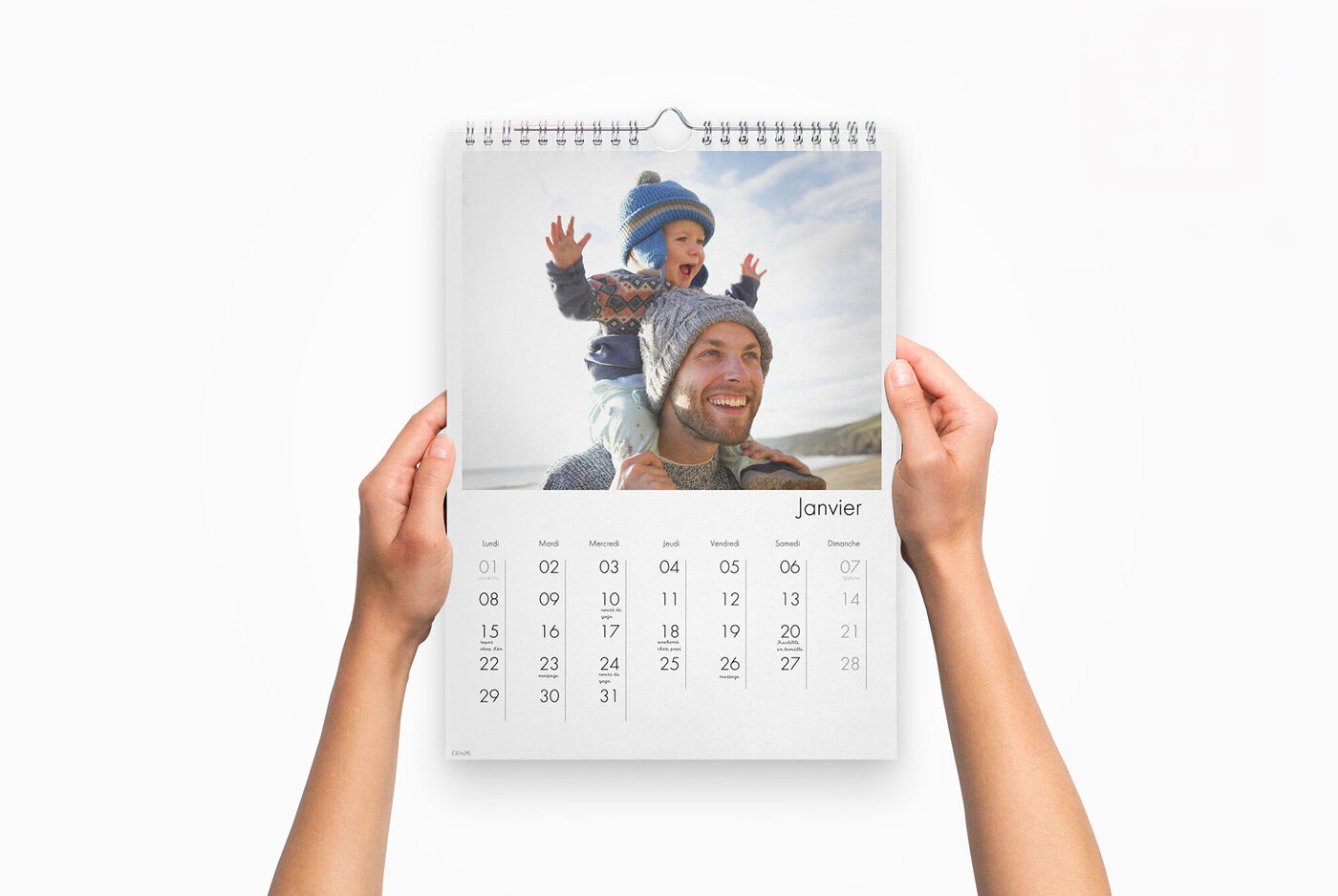 Un calendrier personnalisé entre les mains d'une personne, avec la photo d'un enfant sur les épaules de son père