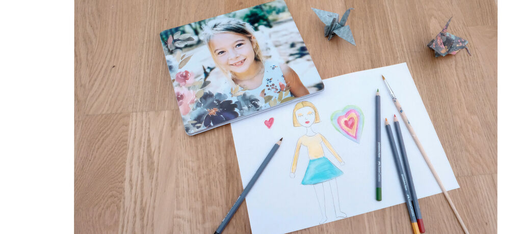 Image créative avec le dessin d'une personne et des crayons colorés sur un sol en bois ; un livre photo en arrière-plan