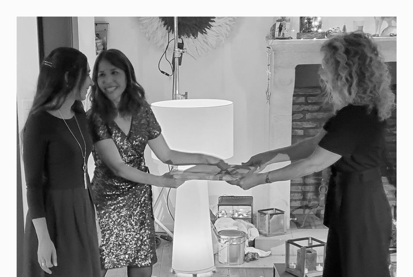 Trois femmes échangent des cadeaux dans une pièce chaleureuse décorée.