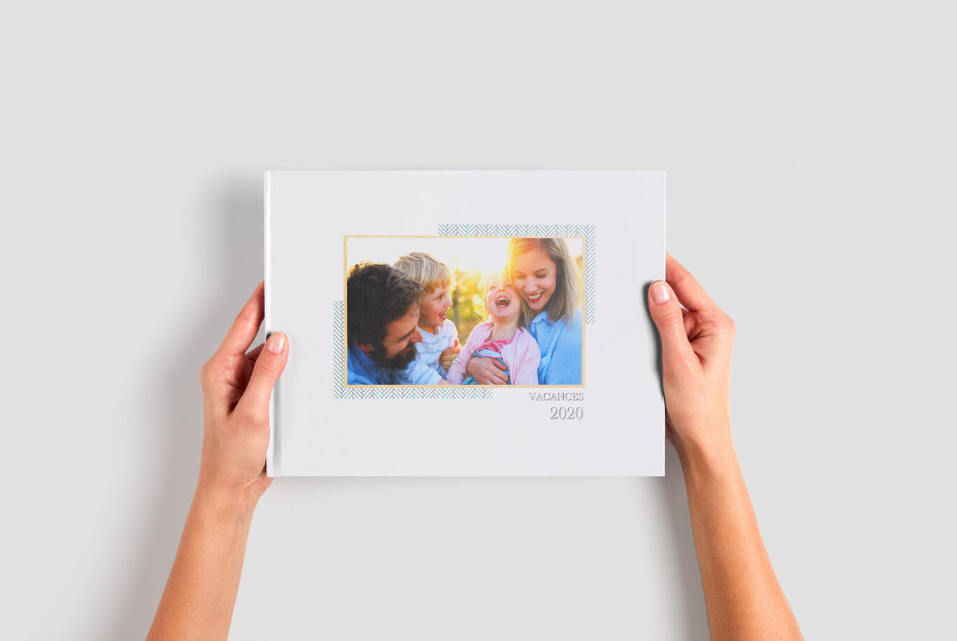 2 mains tenant un petit album photo au format paysage avec des photos de famille