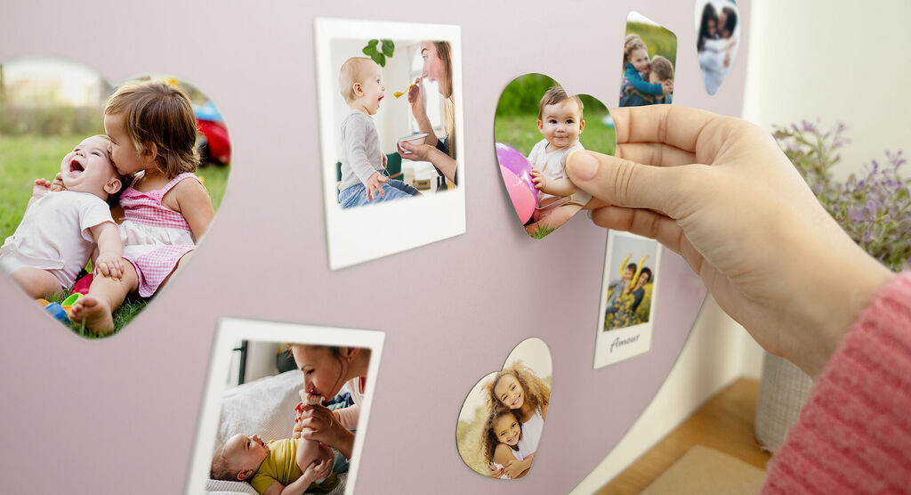 Main tient une photo de moments heureux sur un mur avec d'autres images.