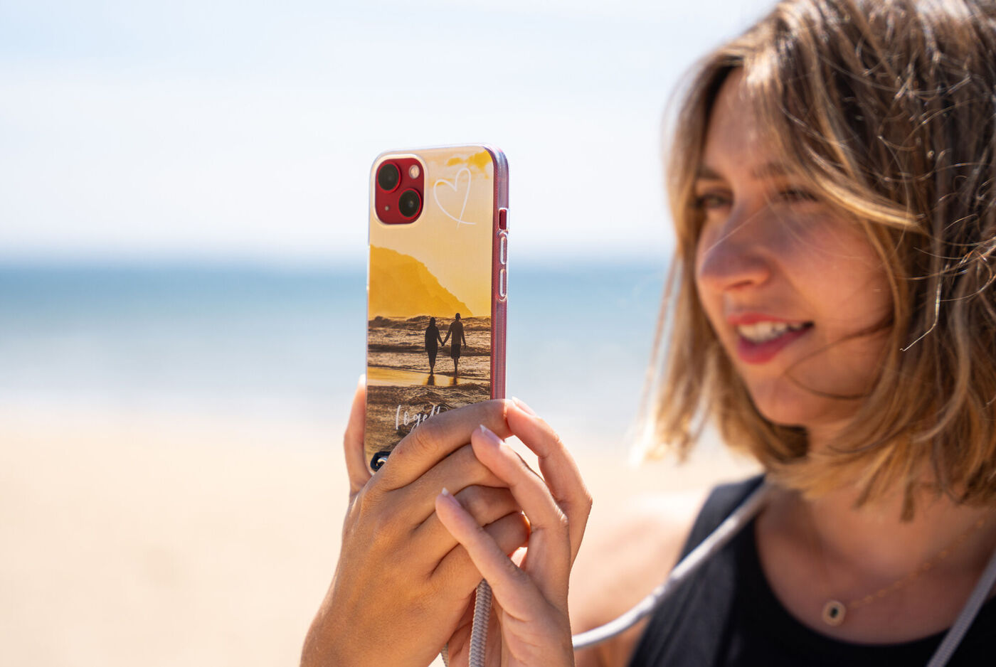 Une personne tient un téléphone avec un beau design sur la plage.