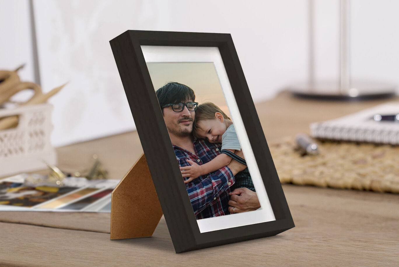 Une photo aimante dans un cadre noir, montrant un père avec son enfant. Cela dégage joie et proximité.