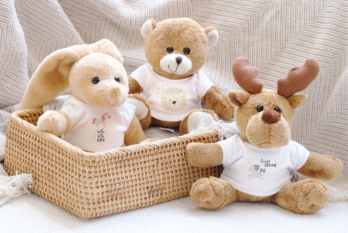 Trois peluches adorables dans un panier, un lapin, un ours et un renne, habillés de T-shirts.