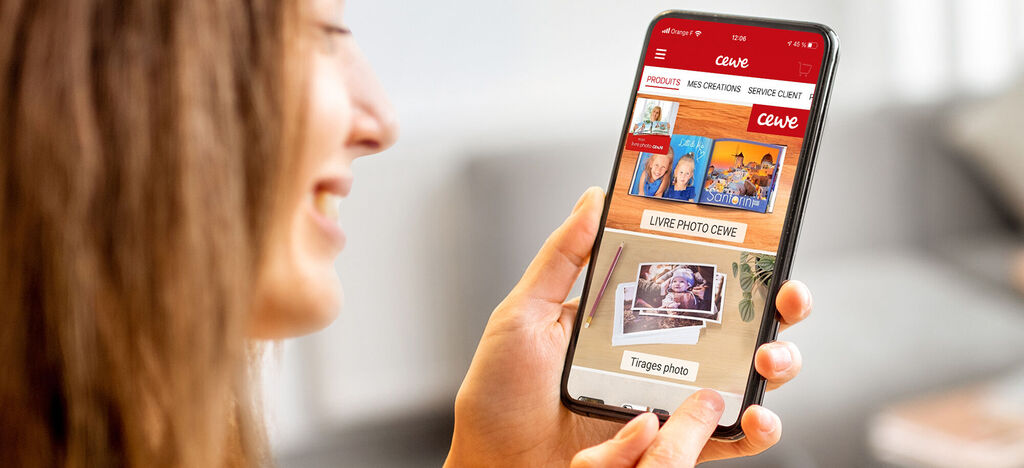 Une personne jeune utilise l'application CEWE World sur un smartphone pour créer des moments photo.