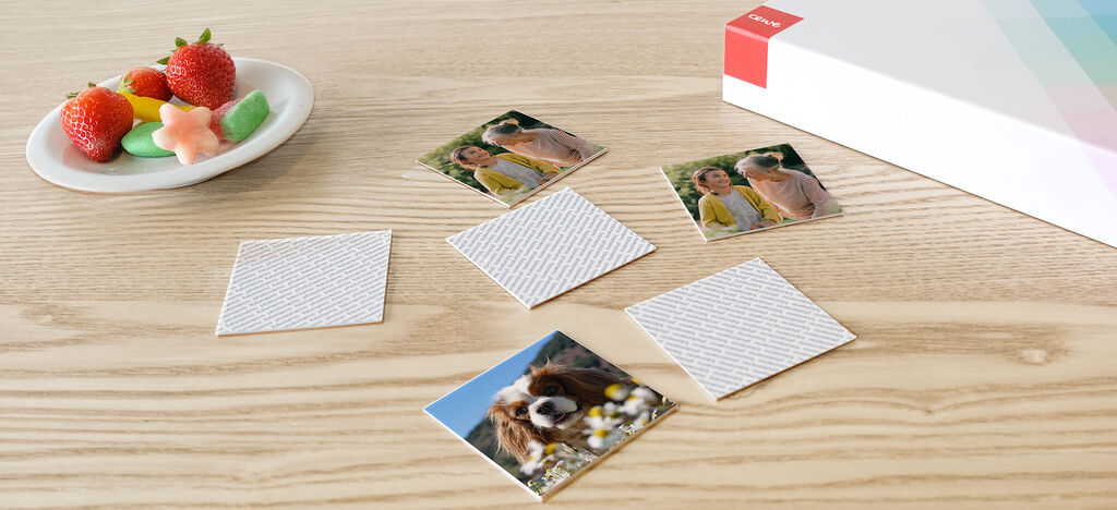 Cinq petites photos sont posées sur une table en bois à côté d'une assiette de fruits et de douceurs