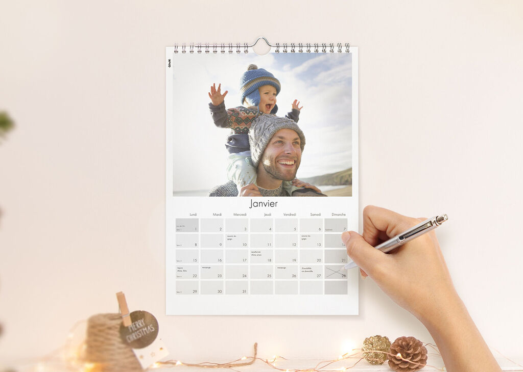 Un calendrier dessiné à la main est accroché au mur. Un enfant rit et porte un chapeau bleu. Il savoure l'instant.