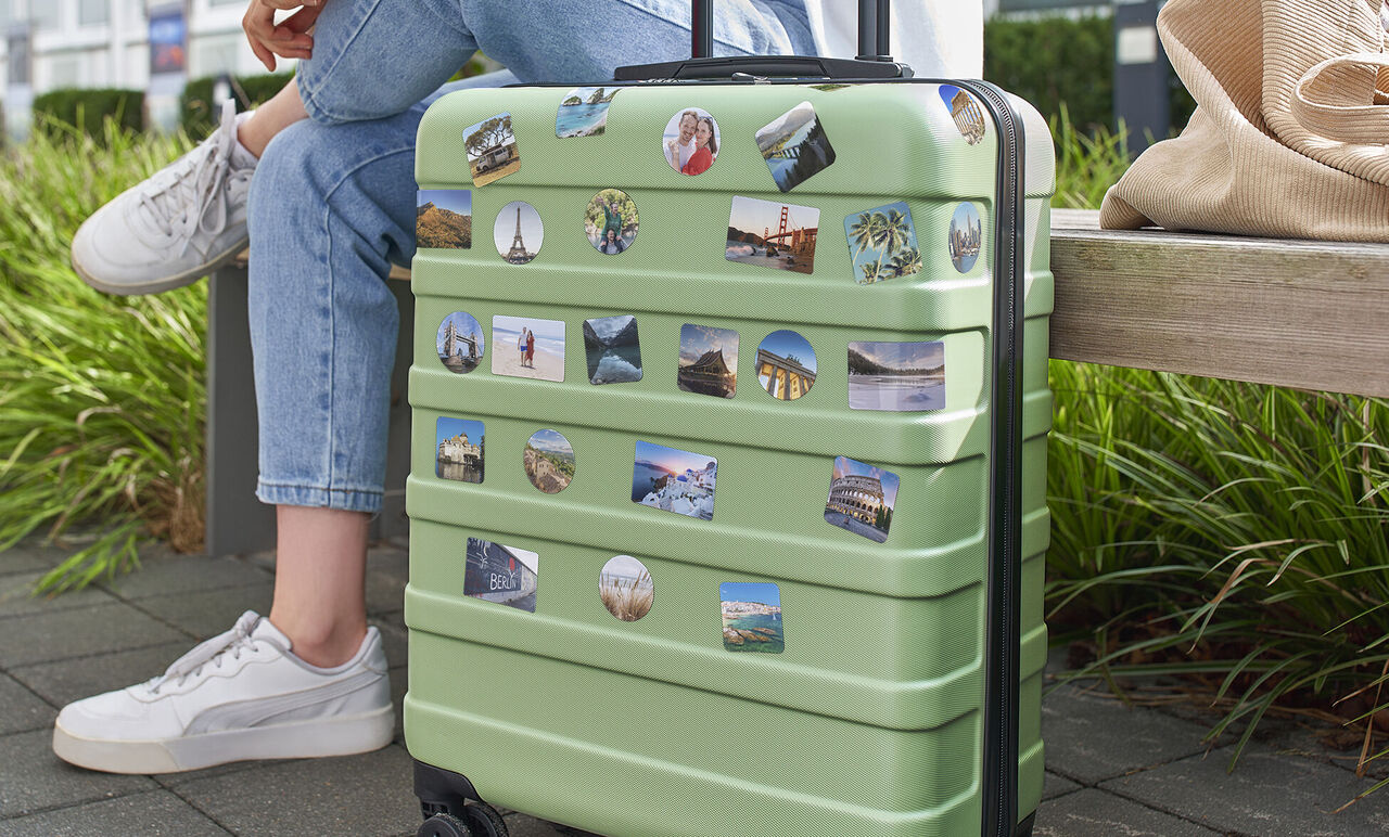 Valise verte avec autocollants souvenirs sur un banc.