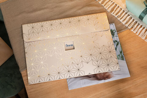 Une belle enveloppe avec un motif géométrique doré et le nom Anna, posée sur une table en bois.