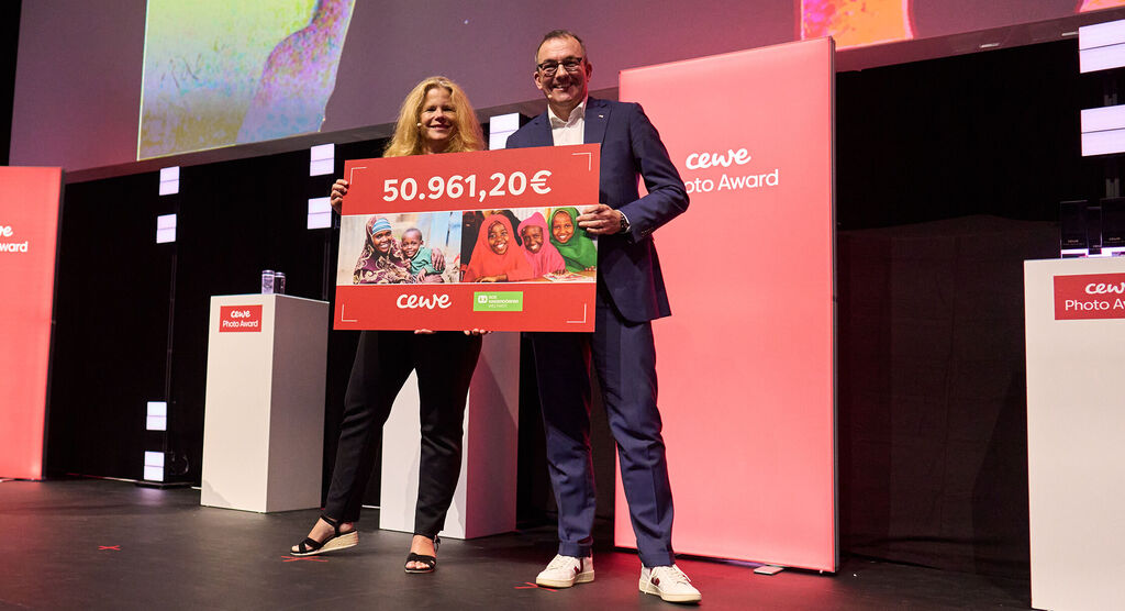 Deux personnes tiennent un gros chèque de 50 961,20 euros du CEWE Photo Awards.