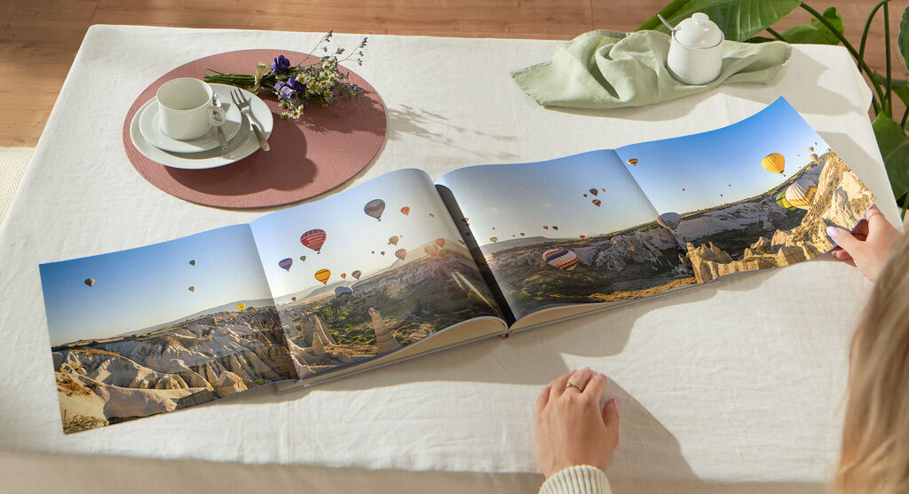 Livre Photo CEWE avec double page panoramique montrant une grande photo de paysage avec montgolfières