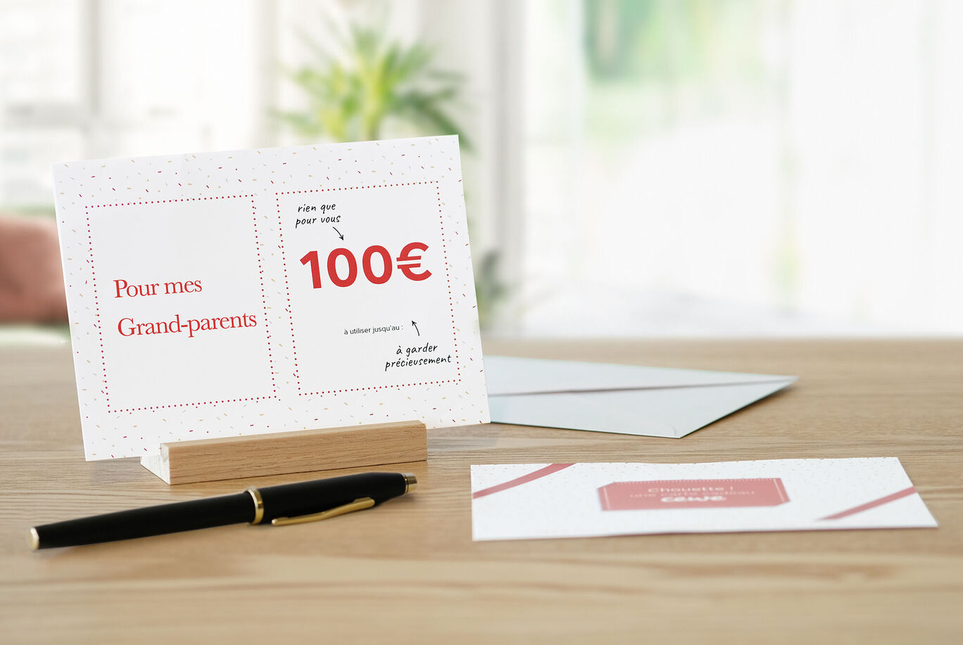 Une carte de vœux CEWE avec un bon de 100 euros pour les grands-parents sur une table.