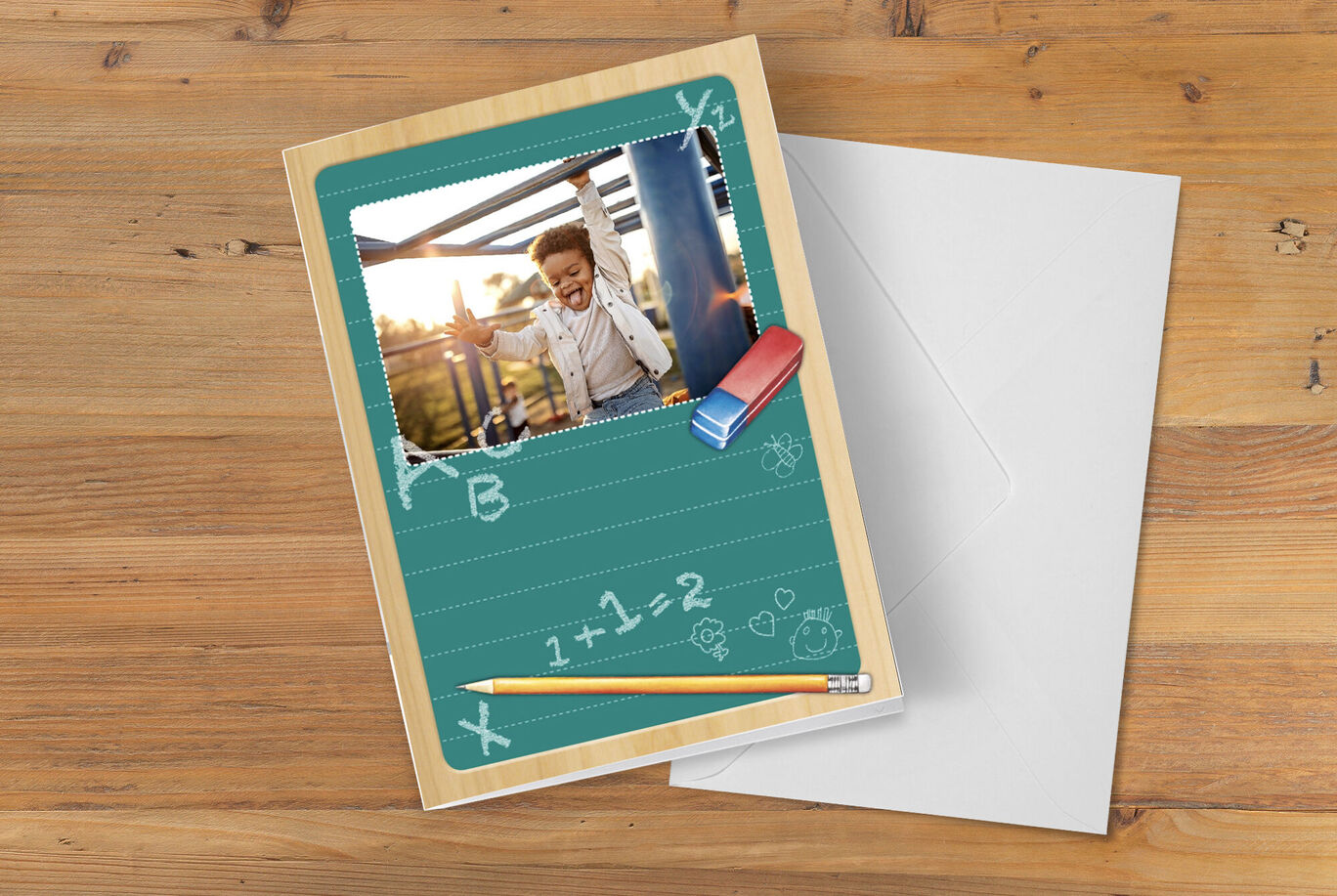 Carte humoristique avec une photo d'un enfant souriant, entouré d'outils scolaires et d'un fond vert.