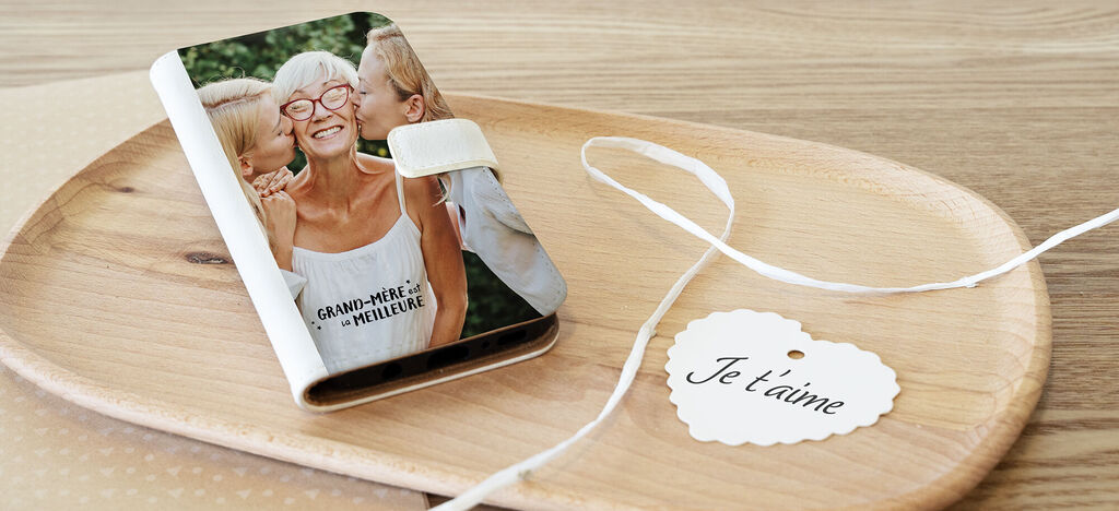 Un livre photo CEWE affectueux est posé sur une planche en bois. À côté, une petite carte dit « Je t'aime ».