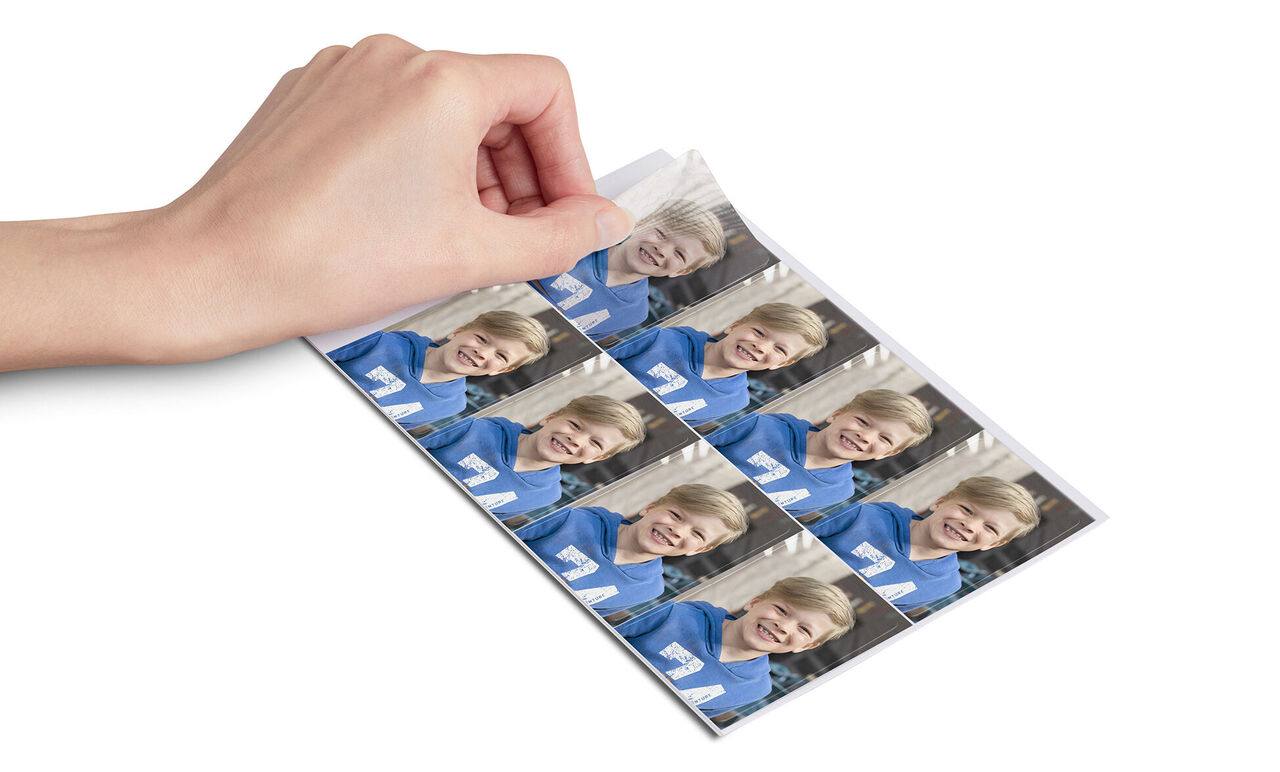 Une main montre des tirages photo d'un garçon en vêtements bleus.