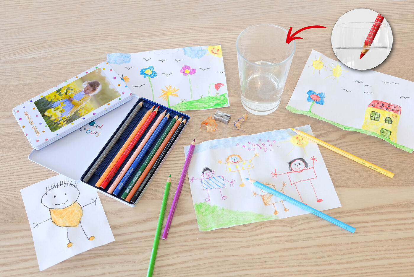 Dessins d'enfants colorés sur une table, des fournitures de peinture à disposition.