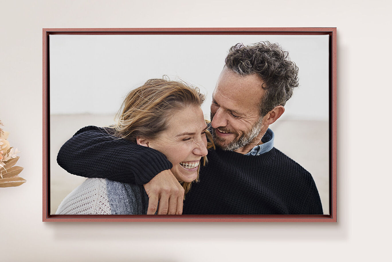Un couple pose joyeusement, s'étreignant dans une pièce lumineuse. Leur visage est flou.