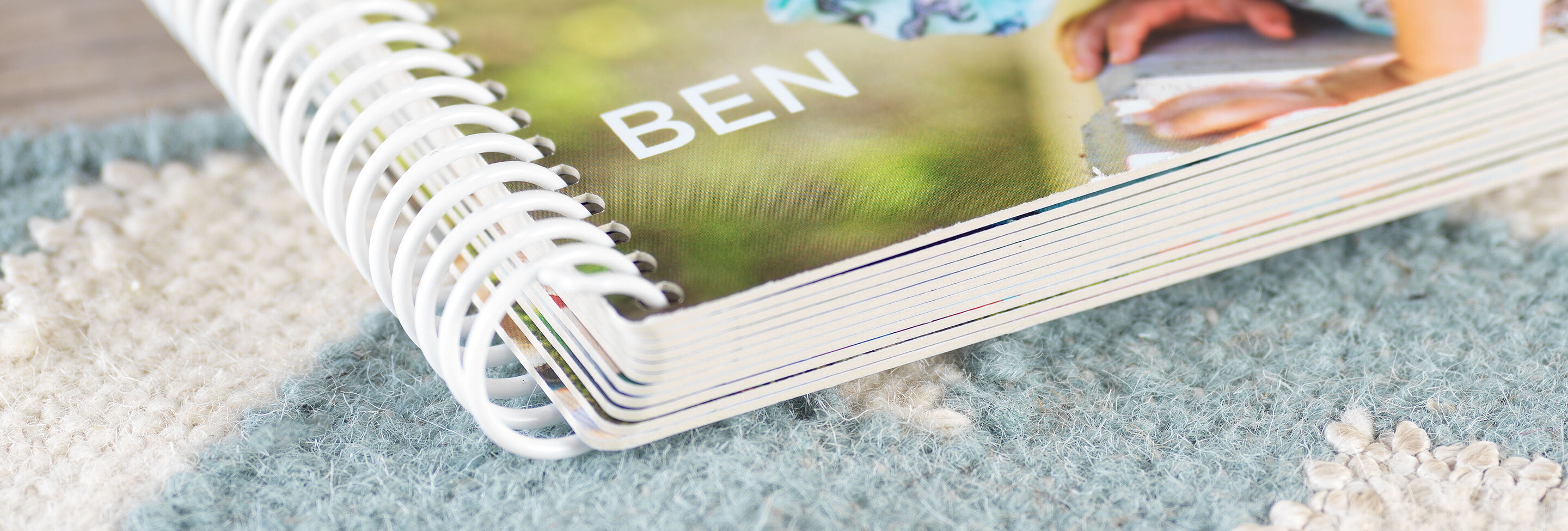 Détail d'un CEWE Photo Book ouvert nommé 'BEN' sur un tapis.