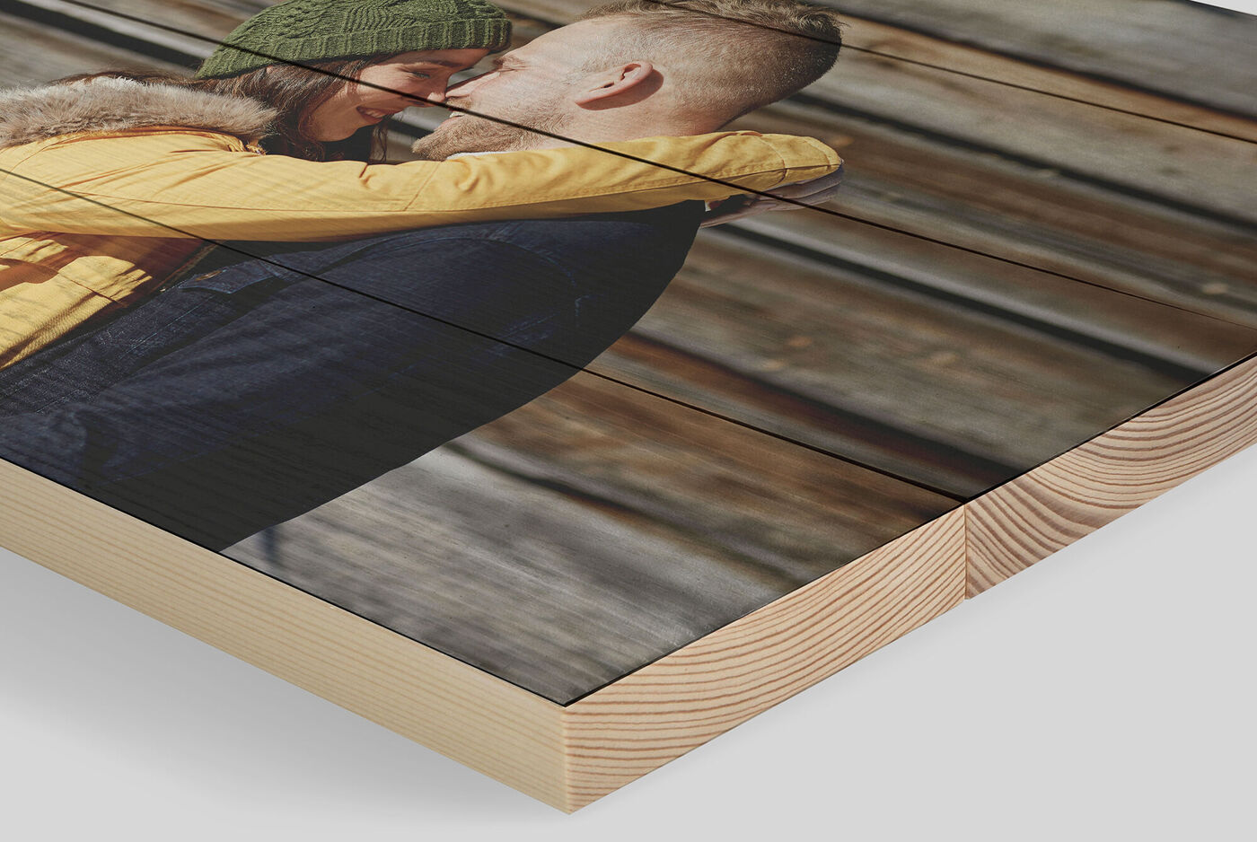 Un couple s'enlace devant un fond en bois