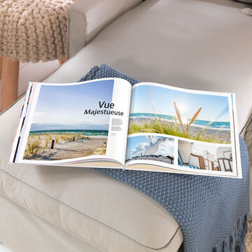 un grand album photo carré XL 30x30 cm ouvert qui montre la mer et écrit dessus "Vue Majestueuse""