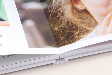 Zoom sur la reliure d'un album photo A4 paysage ouvert et avec ouverture à plat montrant des photos d'enfants