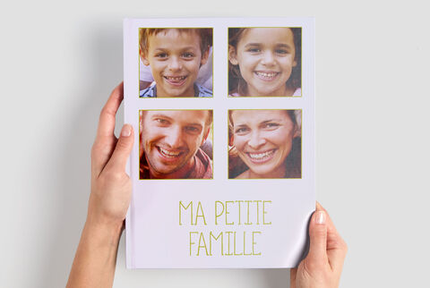 Une personne tient un livre photo avec des images de sa famille.