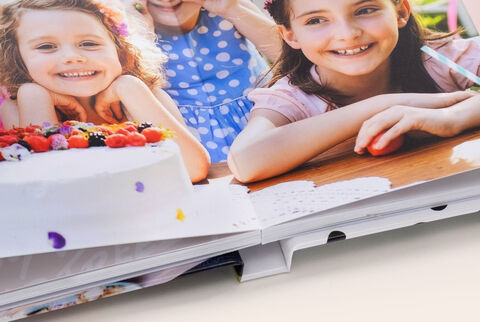 Zoom sur la reliure d'un album photo A5 paysage ouvert et avec ouverture à plat montrant des photos d'enfants souriants