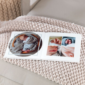 Un album photo carré 21x21 cm ouvert et montrant des photos de bébés