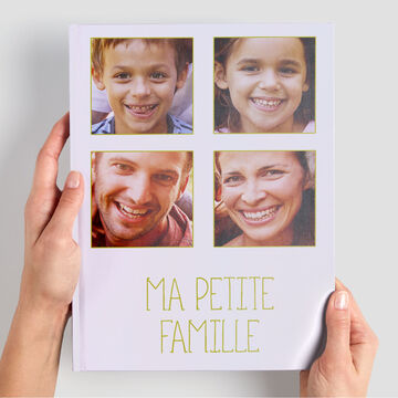 Des mains tenant un livre photo CEWE intitulé "Ma Petite Famille".